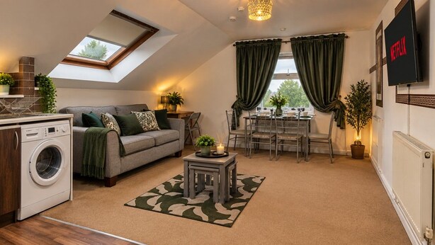 A compact living space with a washing machine, a sofa, a dining table, and a TV mounted on the wall. - *F15GH* Setup for your most relaxed & amazing stay + Free Parking + Free Fast WiFi (West Yorkshire)
