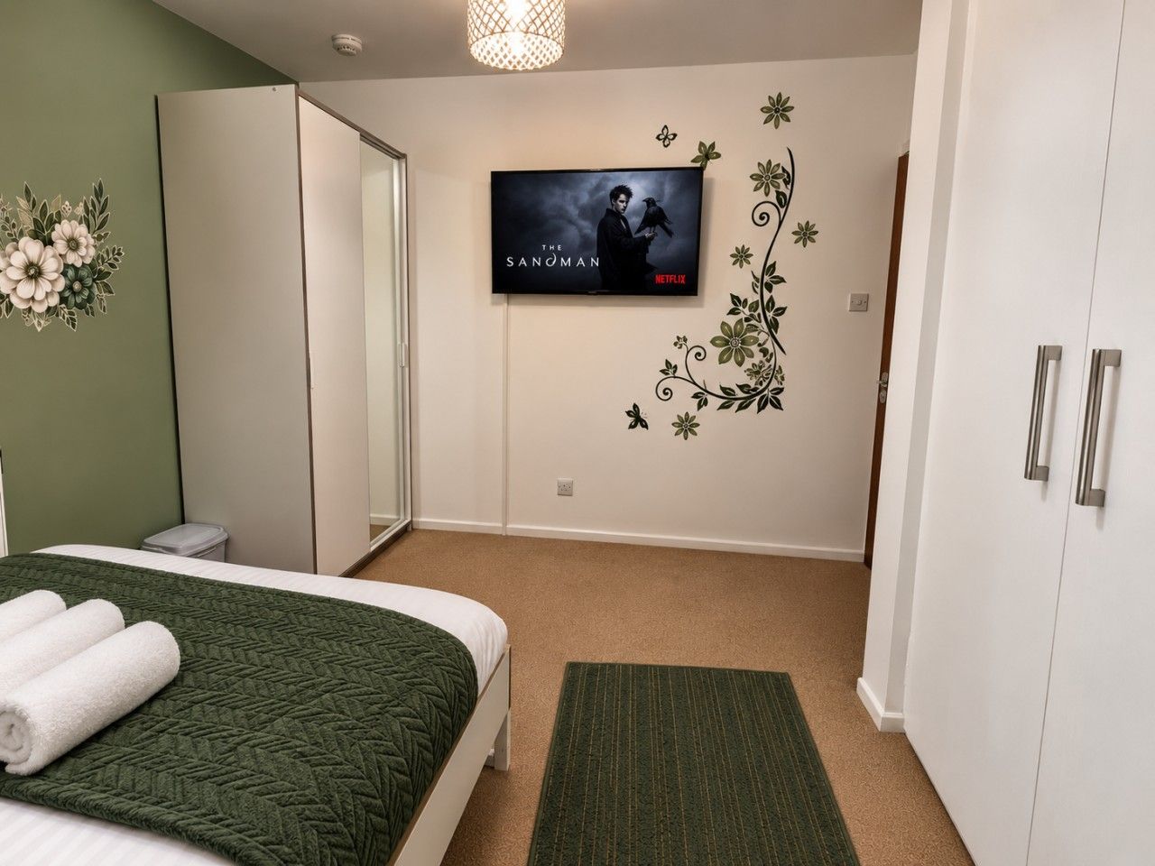 A bedroom with a bed, a television mounted on the wall, and a wardrobe.