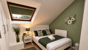 A bedroom with a skylight, a bed with green bedding, a bedside table with a lamp, and a green rug. - *F15GH* Setup for your most relaxed & amazing stay + Free Parking + Free Fast WiFi (West Yorkshire)