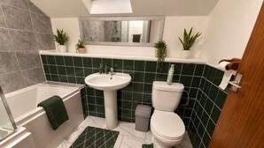 A bathroom with a bathtub, sink, toilet, and green-tiled walls. - *F15GH* Setup for your most relaxed & amazing stay + Free Parking + Free Fast WiFi (West Yorkshire)