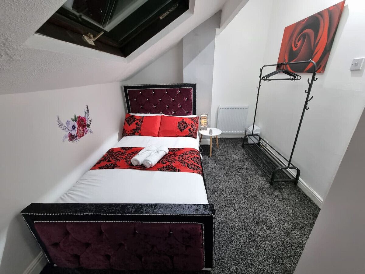 Ein Schlafzimmer mit einem Bett, einem Heizkörper, einer Stehlampe und einem Bild an der Wand.