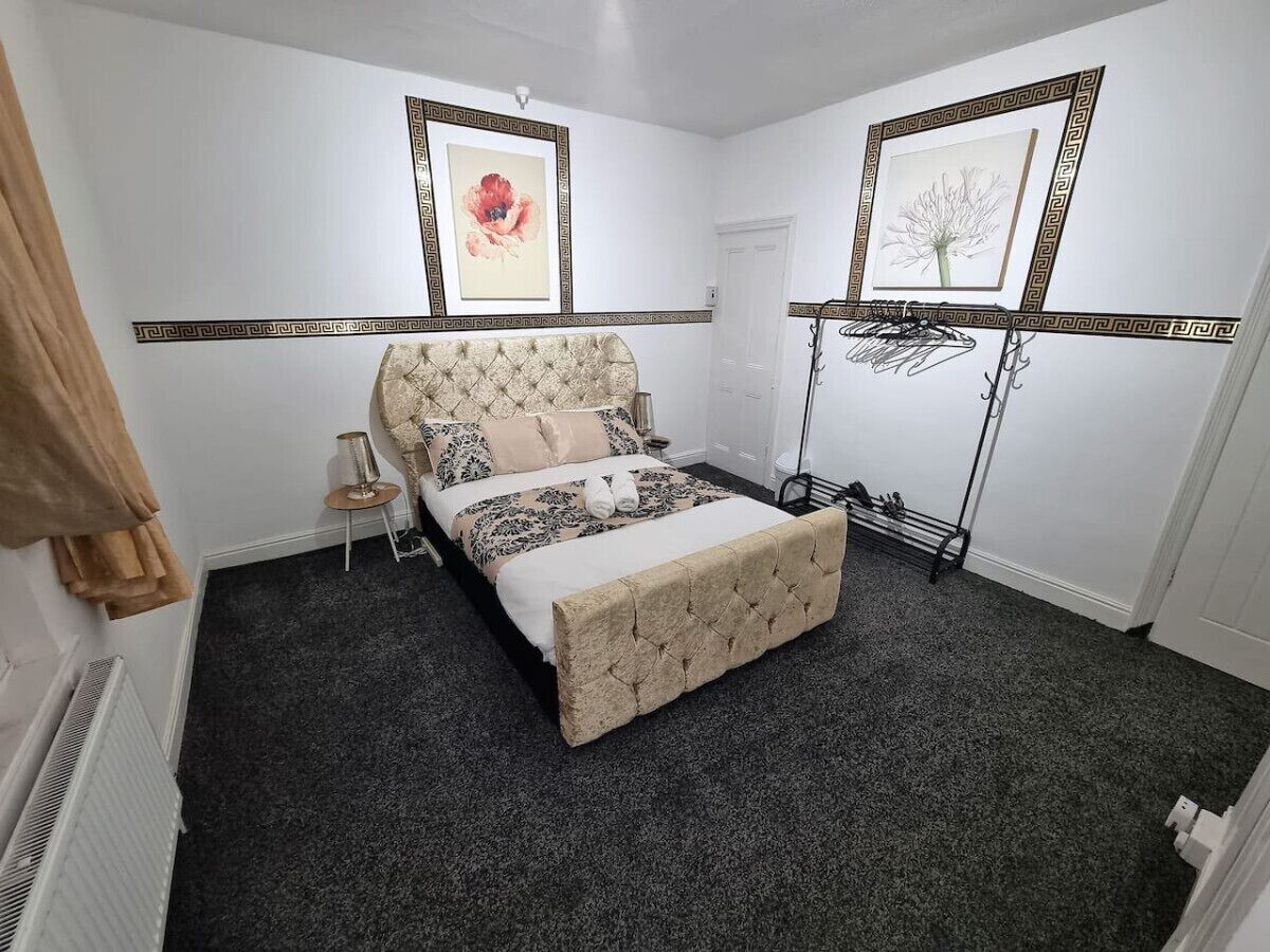 A bedroom with a bed, a bedside table, a radiator, and a picture frame on the wall.