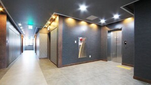 Un pasillo moderno con un ascensor empotrado en la pared y un detector de incendios.
