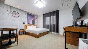 Una habitación de hotel moderna con cama, escritorio, silla, televisor y cafetera.