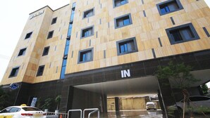 Un edificio de varios pisos con un diseño moderno, que destaca un cartel prominente de 'RAON' a la izquierda.