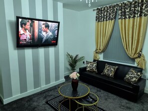 Un salon avec un téléviseur, un canapé et des coussins décoratifs.