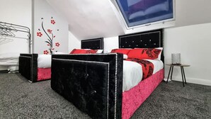 A bedroom with two beds, a skylight, a wall decoration, and a small table. - *11BR* Setup for your most amazing relaxed stay + Free Parking + Free Fast WiFi (West Yorkshire)