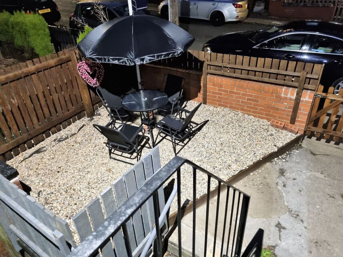 A patio area with a grill, outdoor seating, and a gravel surface.