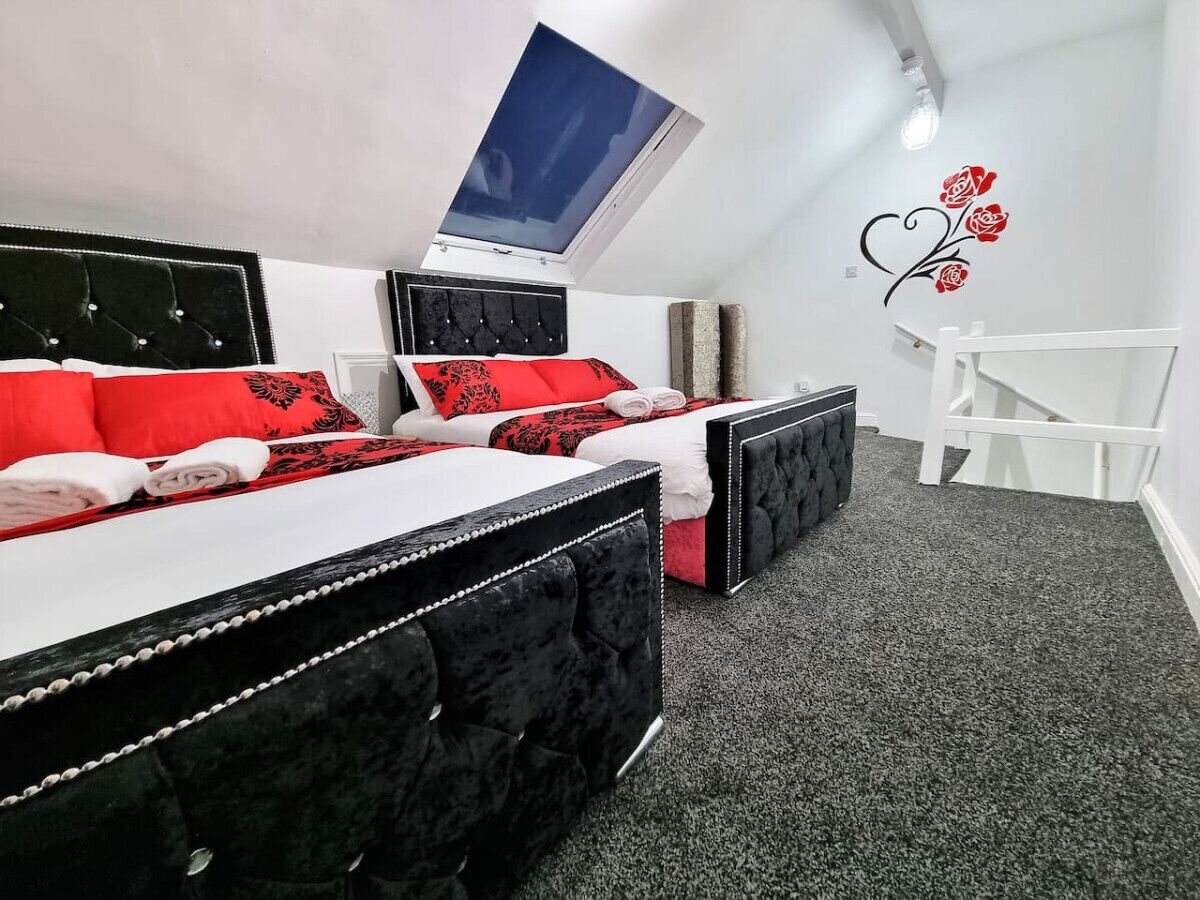 A bedroom with two beds, a skylight, a white chair, and a wall decoration.
