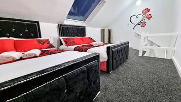A bedroom with two beds, a skylight, a white chair, and a wall decoration.