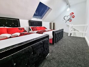 Une chambre avec deux lits, une lucarne, une chaise blanche et un élément décoratif mural.