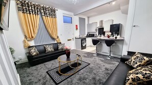 A modern living room with a black sofa, a round coffee table, and a black and gold patterned rug. - *11BR* Setup for your most amazing relaxed stay + Free Parking + Free Fast WiFi (West Yorkshire)
