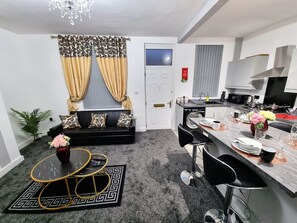 A compact living space with a sofa, dining table, and kitchen area.