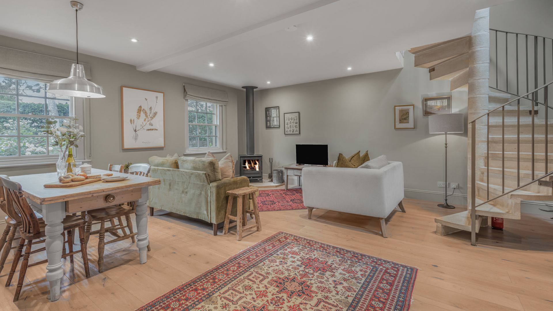 A spacious living area with a fireplace, a dining table, and a staircase.
