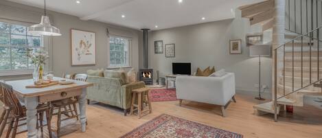 A spacious living area with a fireplace, a dining table, and a staircase.