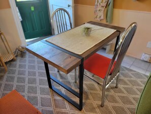 A dining table with a woven placemat, a potted plant, and a red cushion. - Victorian on Herkimer (Hamilton)