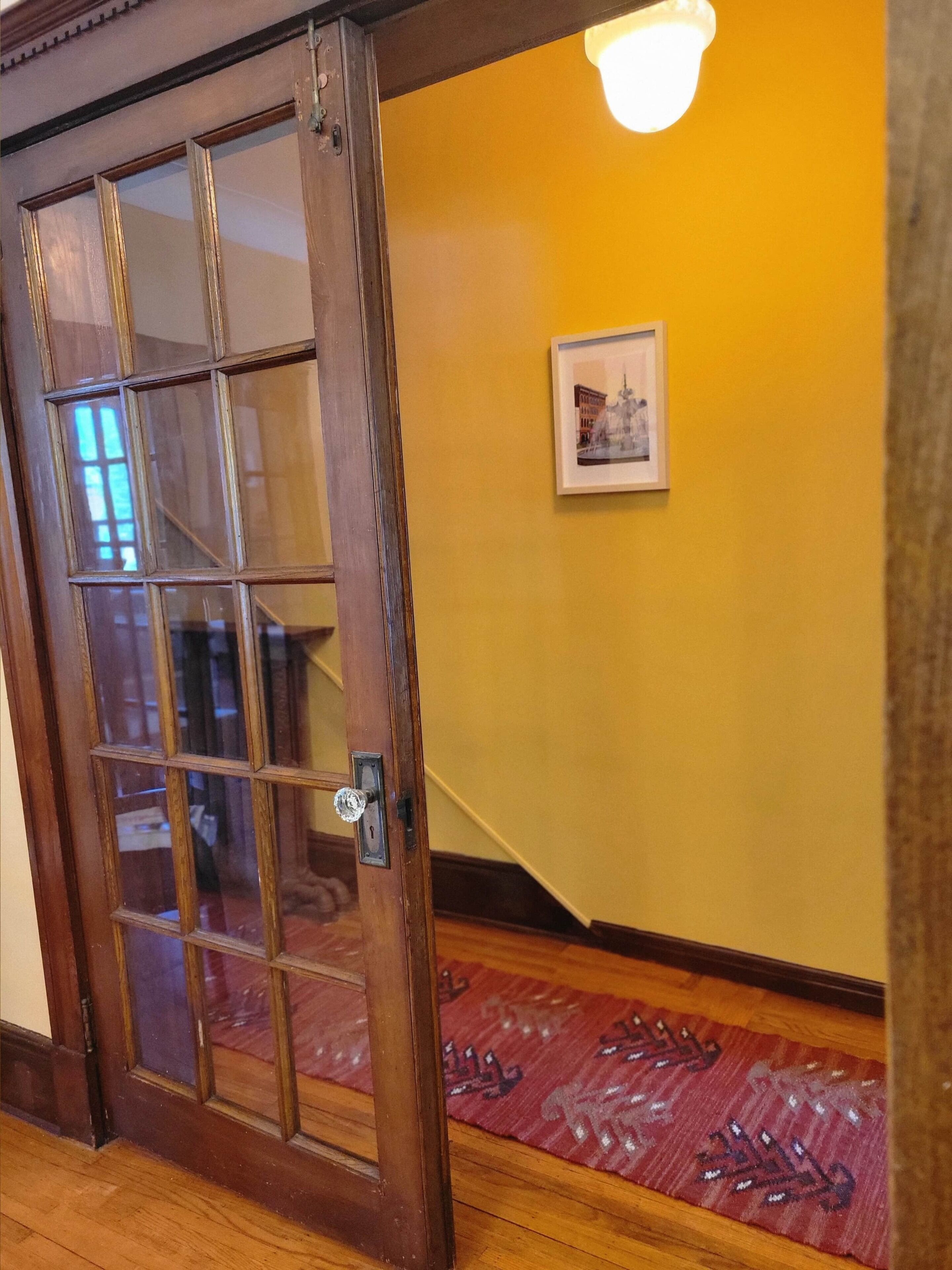A wooden door with glass panels, a yellow wall, and a framed picture.
