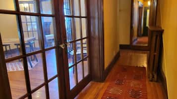 A wooden door with glass panels, a patterned carpet, and a hallway leading to a room with a table and chairs.
