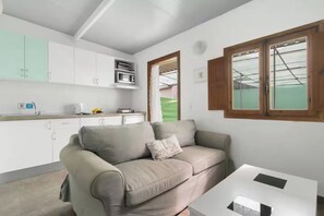 A living room with a sofa, a coffee table, and a kitchen area with cabinets and a microwave.