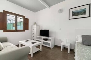 A modern room with a bed, a TV, a desk, and a chair.