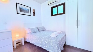 Ein Schlafzimmer mit einem Bett, einem Nachttisch, einem gerahmten Foto, einer Klimaanlage und einem Kleiderschrank.