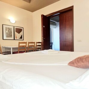 A hotel room with a bed, a table, chairs, and a door leading to a balcony. - Chill&Relax spacious Central BUC (Bucharest)