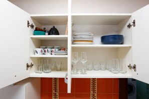 A kitchen cabinet with shelves containing dishes, glasses, and a kettle. - Chill&Relax spacious Central BUC (Bucharest)