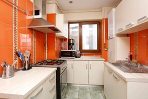 Une cuisine de taille réduite, équipée d’une cuisinière à gaz, d’un four à micro-ondes et d’une fenêtre située au-dessus de l’évier.