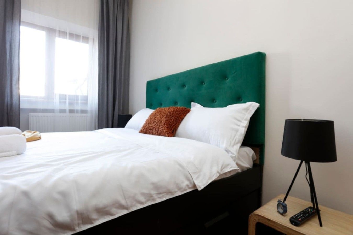 Une chambre d’hôtel avec un lit, une table de chevet, une lampe et une fenêtre avec des rideaux.