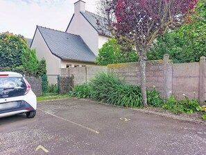 A parking area with a car, a building with a sloped roof, and a stone wall. - Claudel by Interhome (Saint Malo)