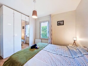 Ein Schlafzimmer mit einem Bett, einem Kleiderschrank, einem Fenster und einer Nachttischlampe.