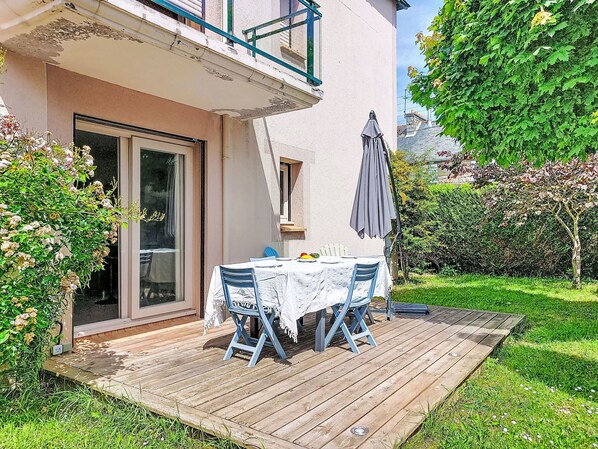 Eine Terrasse mit Tisch und Stühlen, eine Glasschiebetür und ein Balkon mit Geländer.