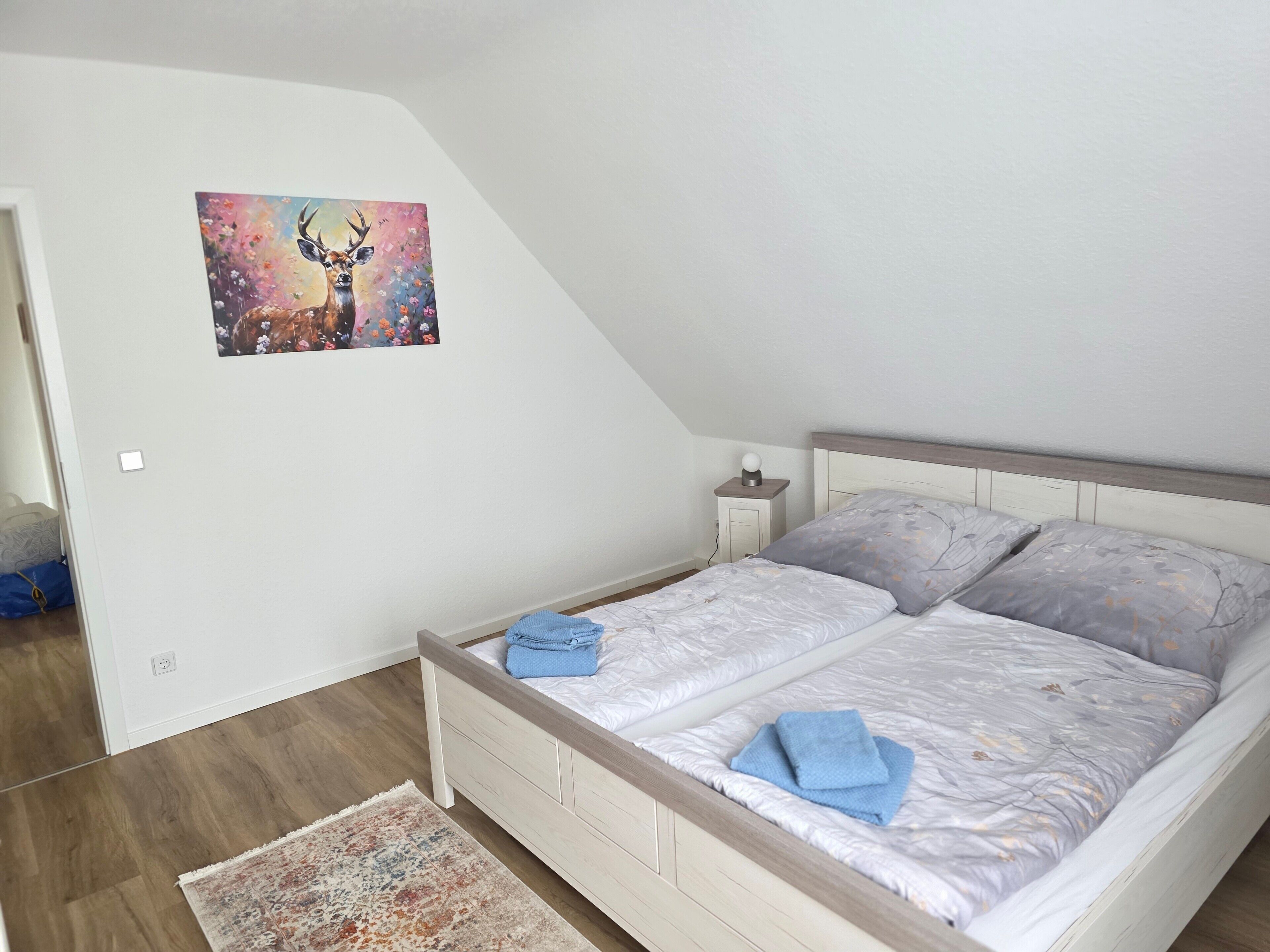 Ein Schlafzimmer mit einem Bett, einem Nachttisch, einem Gemälde und einem Teppich.