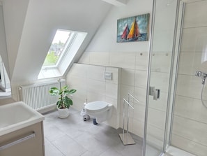 A modern bathroom with a skylight, a toilet, a shower, and a potted plant. - Apartment Rückerts Gartenblick with Shared Garden (Nordhausen)
