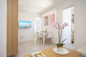 Ein Essbereich mit Tisch, Stühlen, einer Topfpflanze und einem gerahmten Bild an der Wand.