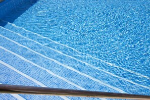 Ein klarer Blick auf ein Schwimmbecken mit blauen Mosaikfliesen und sichtbaren Wellen.