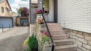 Un edificio residencial con una escalera de piedra, un cartel con el número 26 y una bicicleta estacionada afuera.