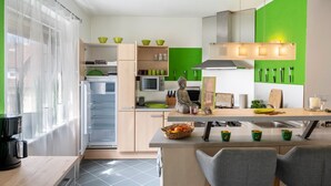 Una cocina moderna con un refrigerador empotrado, una zona de comedor con mesa y sillas, y una pared de acento verde.