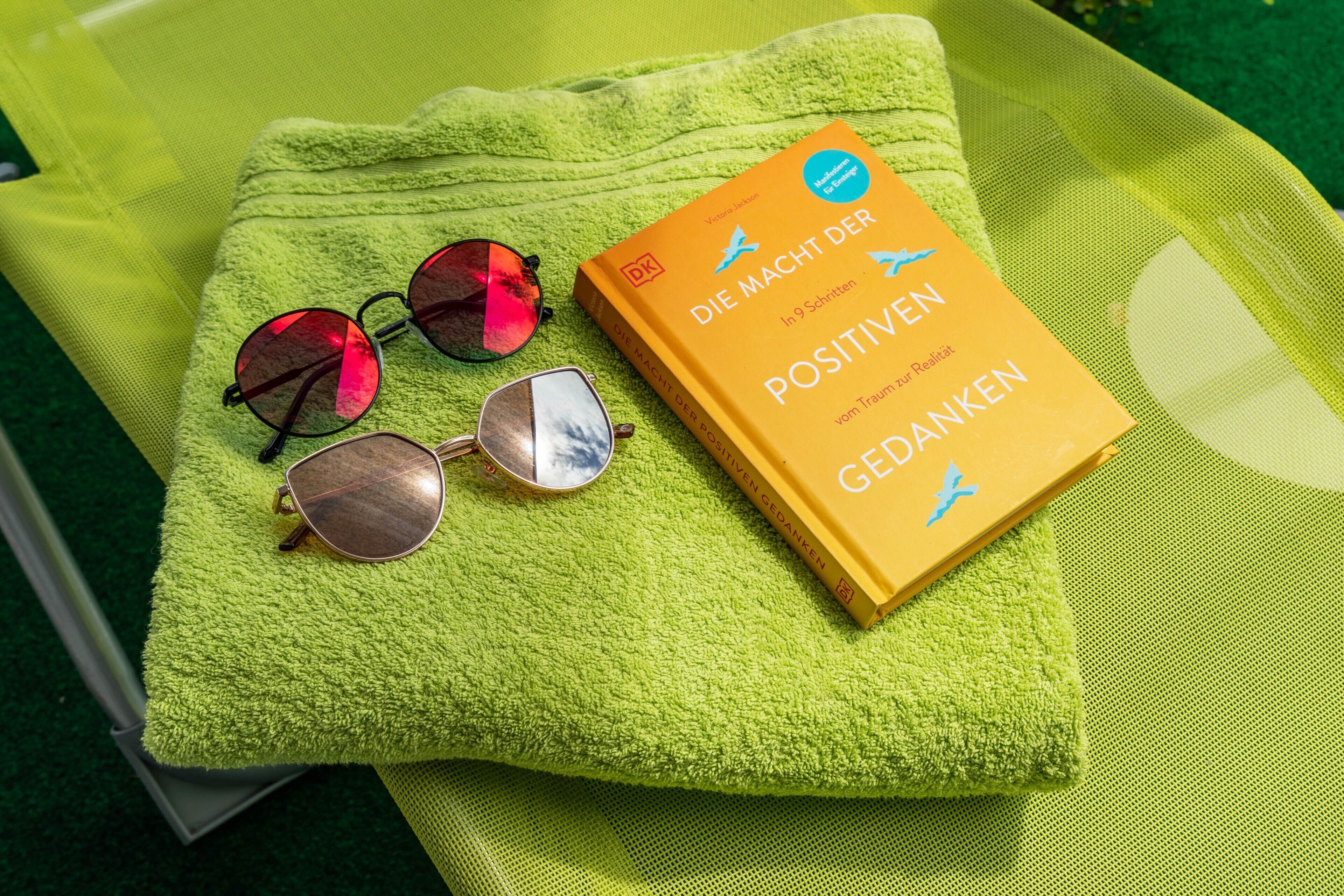 A book titled 'Die Macht der Positiven Gedanken' on a green towel.