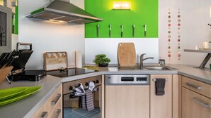 Una cocina moderna con una pared de acento verde, electrodomésticos de acero inoxidable y una variedad de cuchillos exhibidos en la pared.