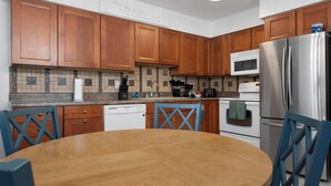 A modern kitchen with wooden cabinets, a stainless steel refrigerator, a microwave, and a dishwasher. - Fantastic 1-bedroom home, short walk to beach. (Holmes Beach)