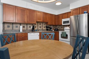 Eine moderne Küche mit Holzschränken, einem Edelstahlkühlschrank, einer Mikrowelle und einem Geschirrspüler.