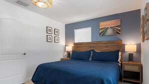 A bedroom with a bed, nightstands, a lamp, a picture on the wall, and a door. - Fantastic 1-bedroom home, short walk to beach. (Holmes Beach)