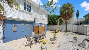 A patio area with outdoor furniture, a decorative wall, and a staircase leading to an upper level. - Anna Maria Island - Newly renovated. Short walk to the beach. New Hot tub. (Holmes Beach)