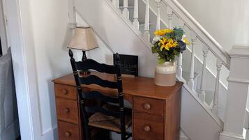 Un escritorio de madera con una silla, una lámpara y un florero con flores.