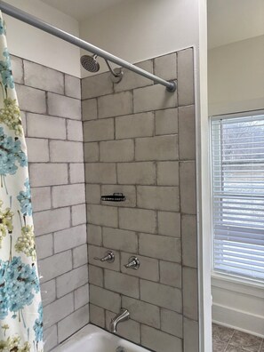 A shower with a rain showerhead, a handheld showerhead, and a handheld faucet.