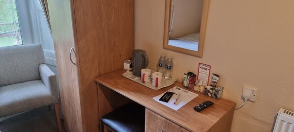 A small kitchenette with a coffee maker, water bottles, a mirror, and a sign for Interland B&B. - Single room-Economy-Ensuite-Mountain view (Crianlarich)