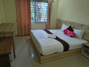 Habitació d'hotel amb llit, escriptori i finestra amb cortines.