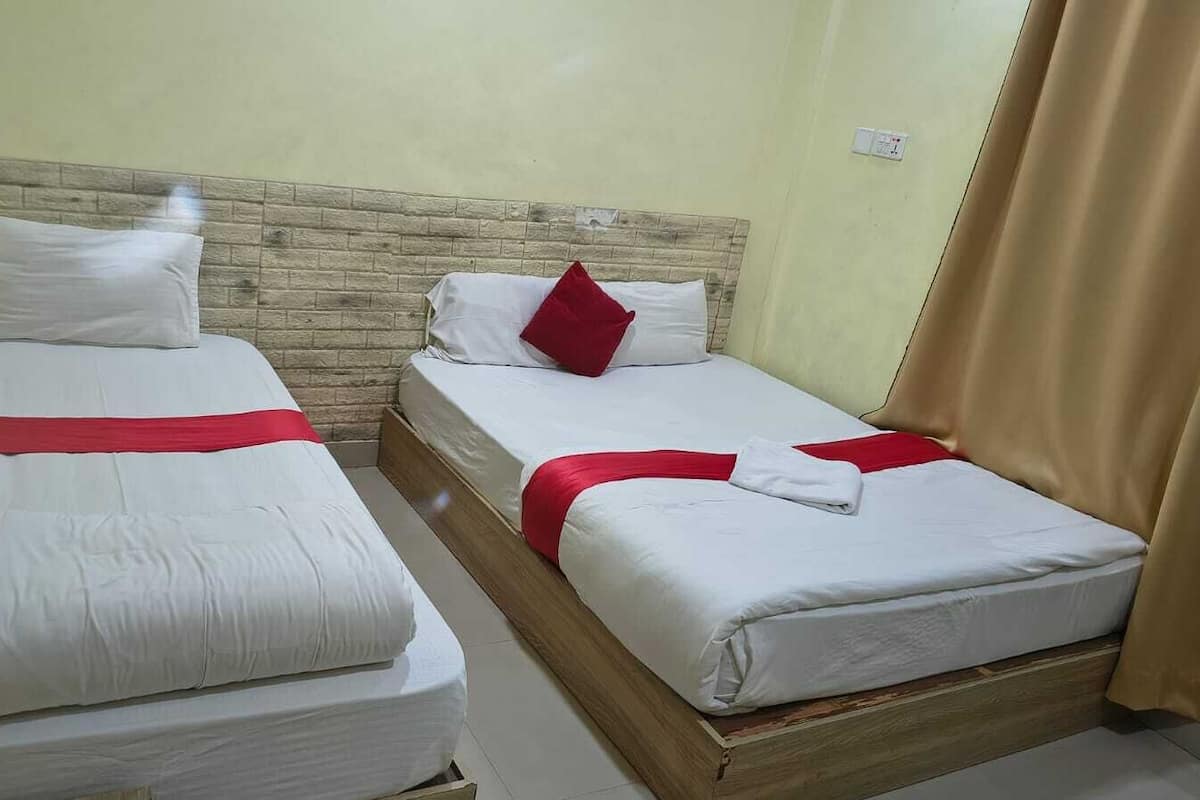 Two single beds with wooden headboards, white bedding, and red accents.