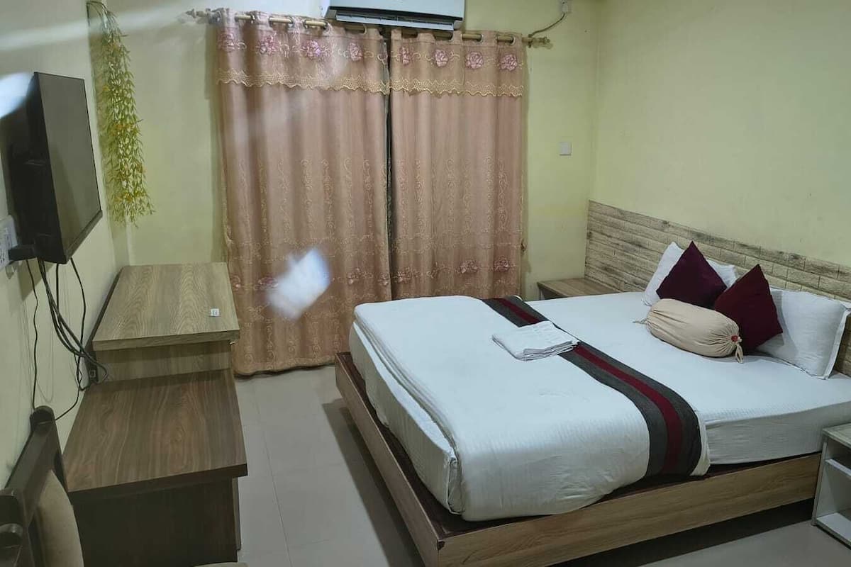 A hotel room with a bed, bedside table, and a television.